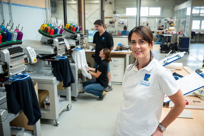 Julie Reisser, responsable commercial et marketing des Ateliers du Sonnenhof devant les 4 machines à broder récemment achetées, en vue du lancement de cette activité.